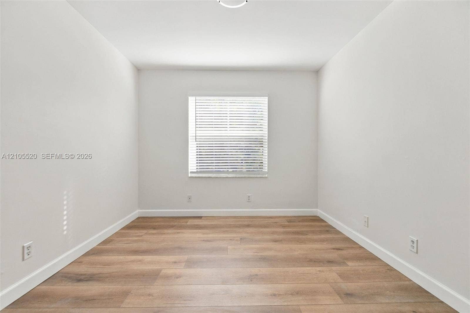 649 Willow Bend Road, Weston, Weston, FL 33327 Neutral interior space featuring wood-finish flooring, crisp white walls, and a single window with horizontal blinds