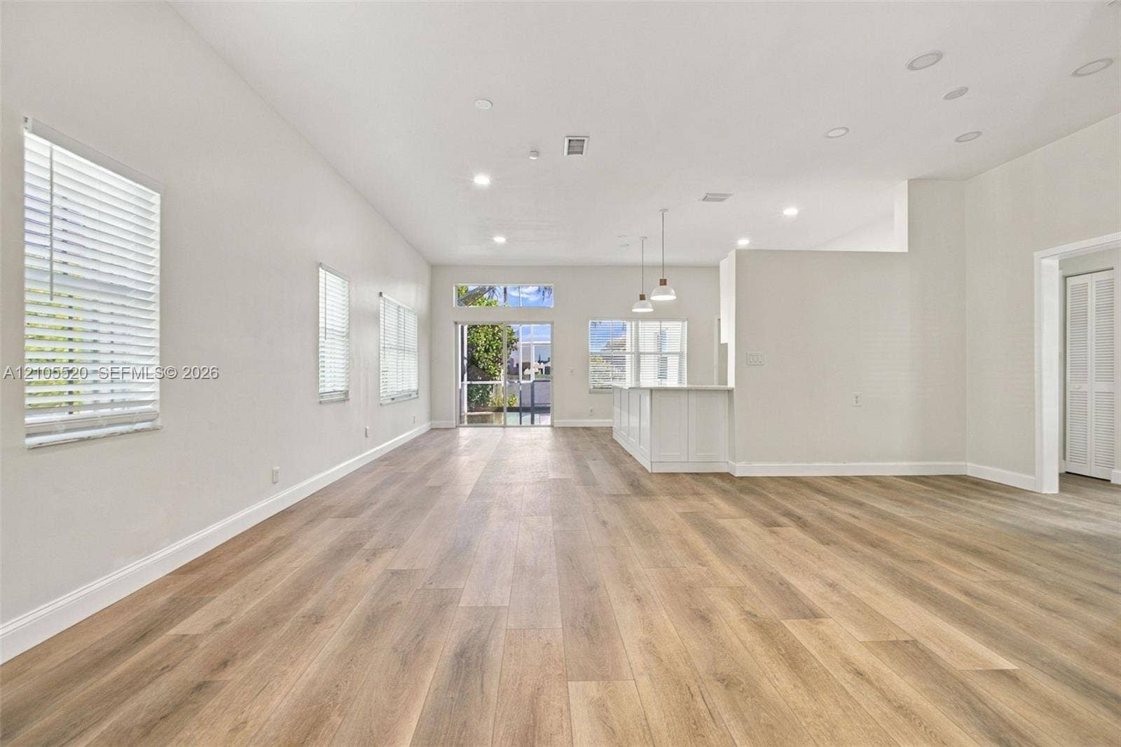 649 Willow Bend Road, Weston, Weston, FL 33327 Open-concept interior featuring wood-finish flooring, recessed lighting, white cabinetry, pendant lighting, and glass sliding doors