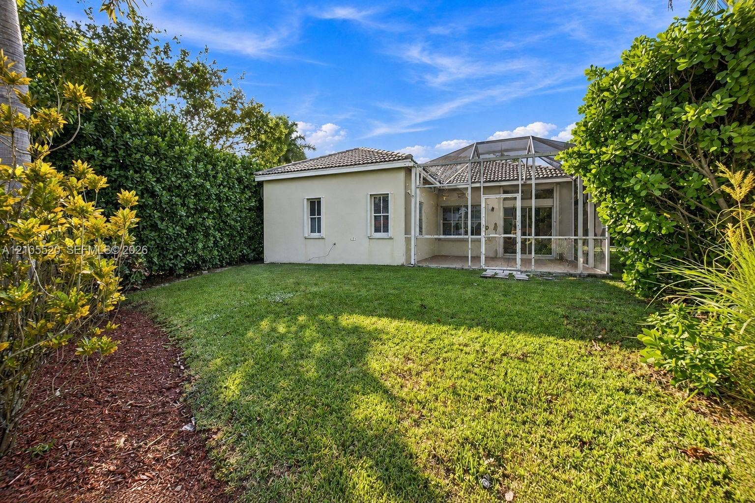 649 Willow Bend Road, Weston, Weston, FL 33327 Rear exterior featuring a screened-in lanai, concrete tile roof, manicured lawn, and perimeter landscaping