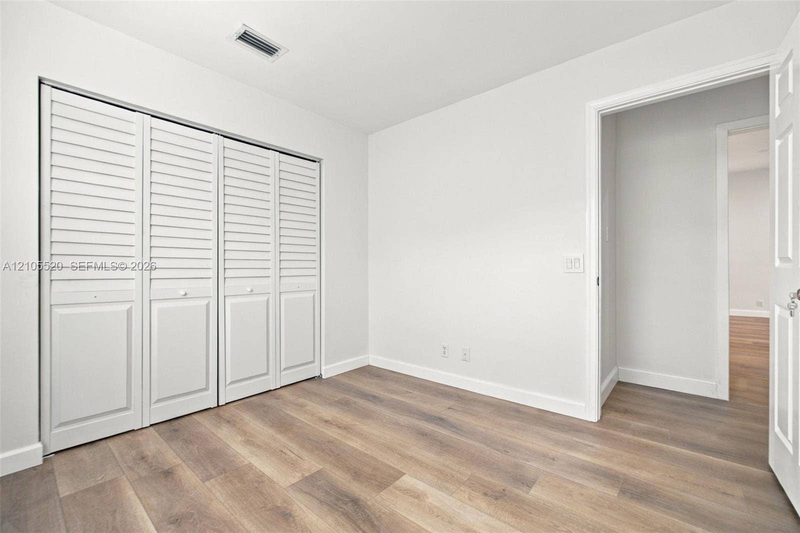 649 Willow Bend Road, Weston, Weston, FL 33327 Neutral-toned room featuring wood-finish flooring, white walls, and a four-panel bi-fold closet with louvered doors