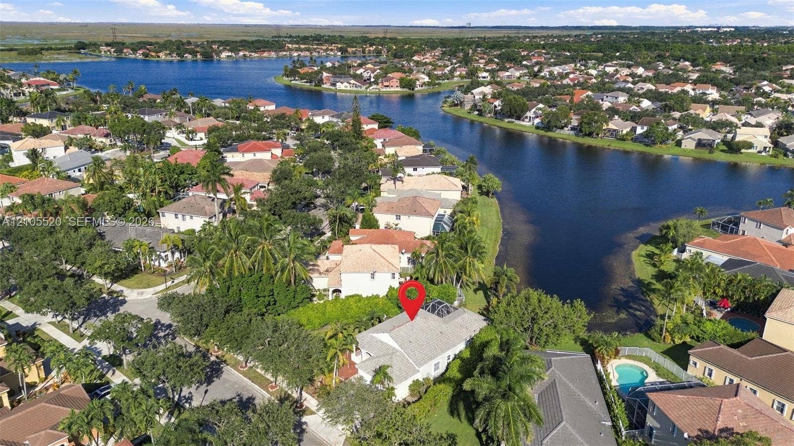 649 Willow Bend Road, Weston, Weston, FL 33327 Aerial perspective of a residential property featuring a screen-enclosed pool, mature palm trees, and proximity to a community lake
