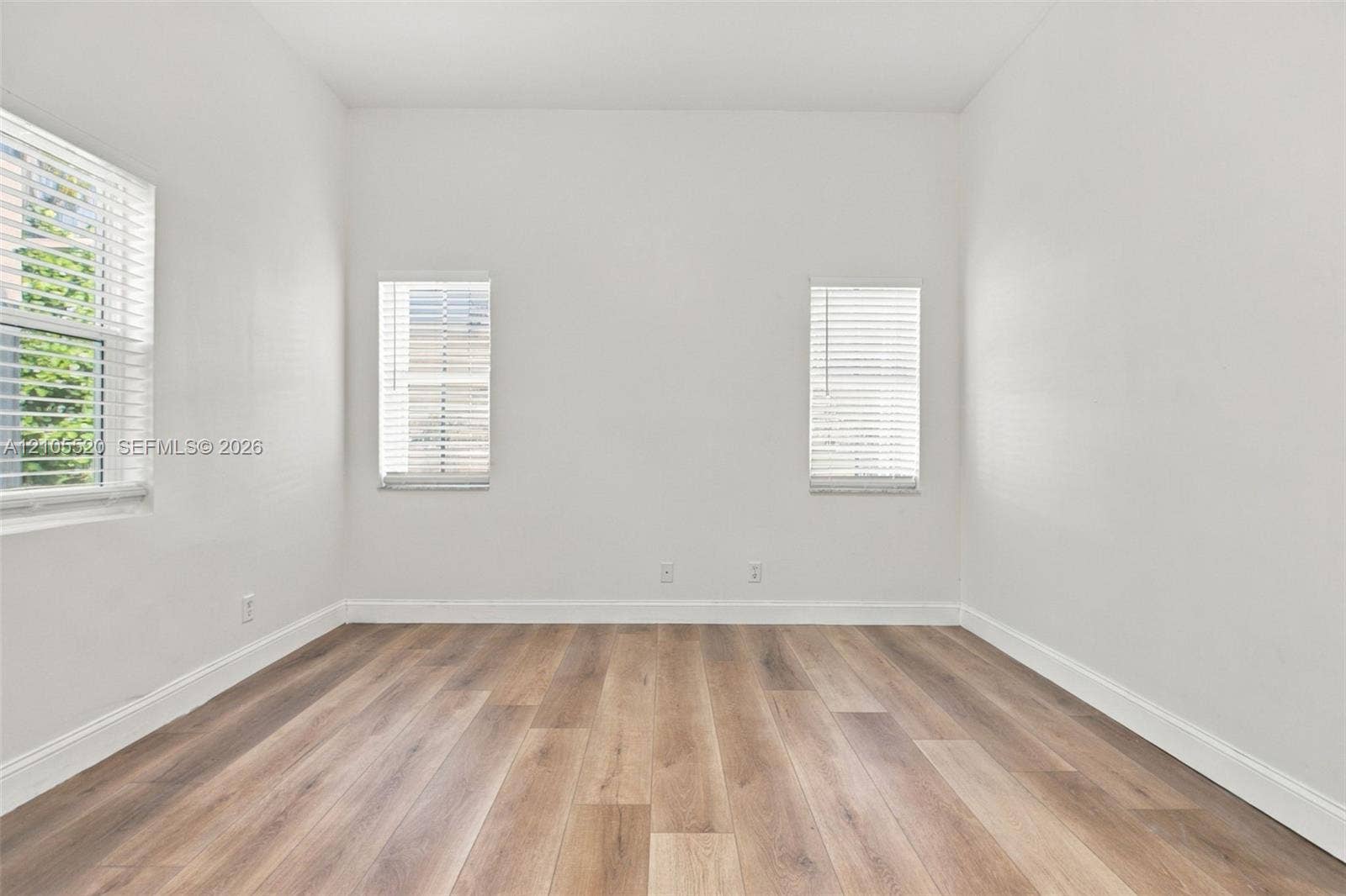 649 Willow Bend Road, Weston, Weston, FL 33327 Interior room featuring wood-finish flooring, white walls, and three windows equipped with horizontal blinds