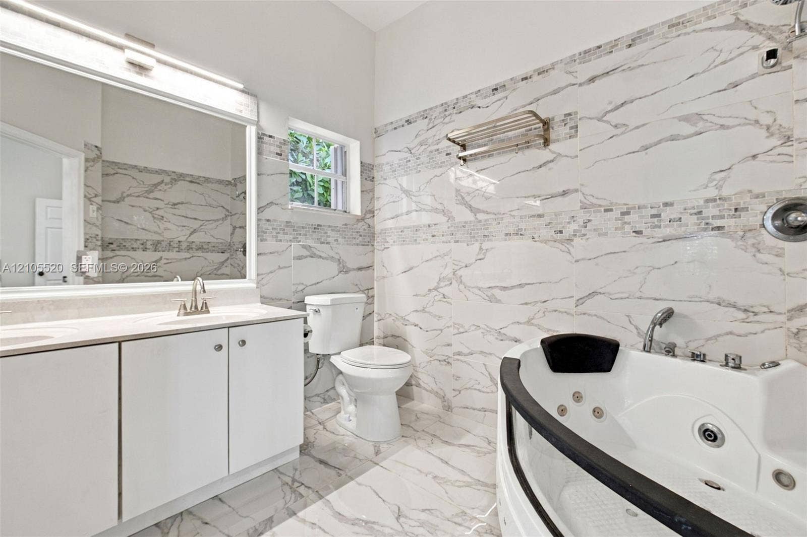 649 Willow Bend Road, Weston, Weston, FL 33327 Bathroom featuring floor-to-ceiling large-format tile with stone-pattern finish, jetted soaking tub, white vanity cabinet with countertop basin, and oversized wall-mounted mirror