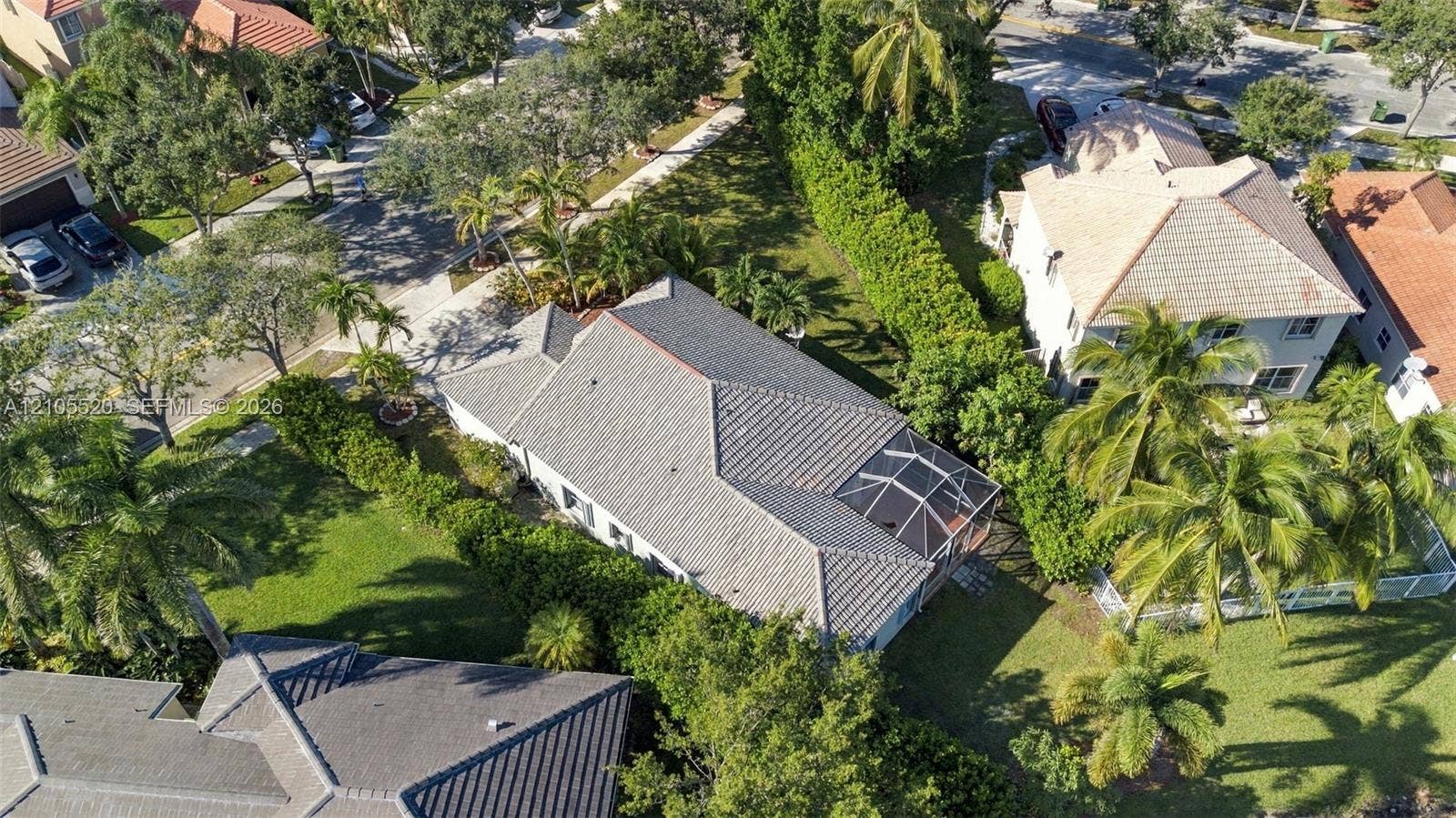 649 Willow Bend Road, Weston, Weston, FL 33327 Aerial perspective of a property featuring a multi-pitched tile roof, an enclosed screened lanai, mature landscaping, and an expansive lawn