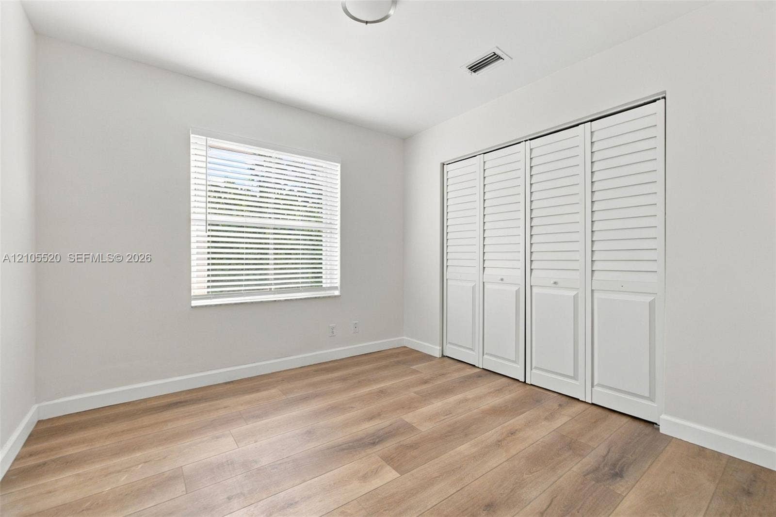 649 Willow Bend Road, Weston, Weston, FL 33327 Interior room featuring wood-finish flooring, a single-panel window with horizontal blinds, and a built-in four-panel louvered closet door