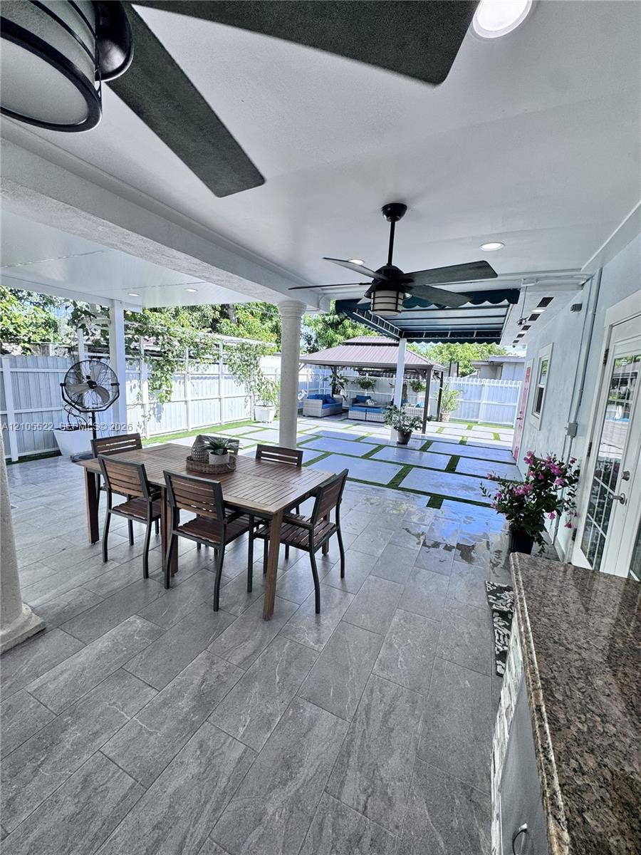 Covered patio with integrated ceiling fans, recessed lighting, and a built-in outdoor kitchen featuring a granite countertop