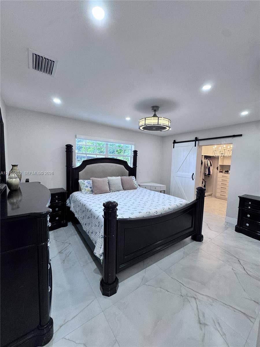 Recessed lighting with a ceiling fan, window with glass blocks, white wood-finish barn door, and large format tile flooring