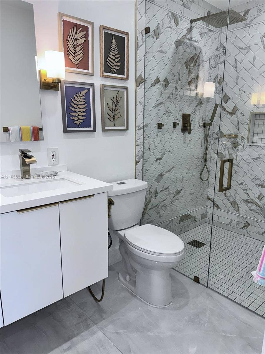 Walk-in shower with glass enclosure, herringbone tile, and rain shower head