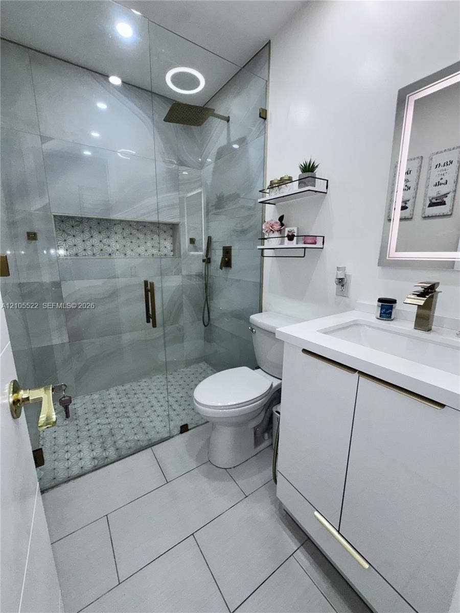 Glass-enclosed shower with a rainfall showerhead, integrated shower niche, and mosaic tile flooring