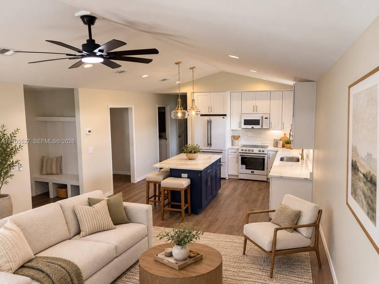 Integrated kitchen and living area featuring a vaulted ceiling and wood-finish flooring