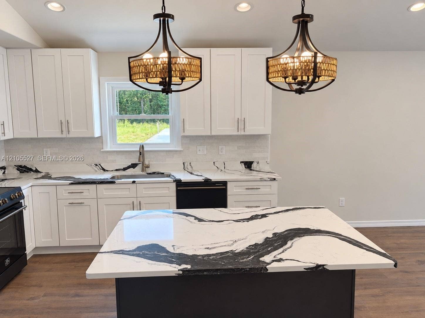 White shaker-style cabinetry, patterned countertops, wood-finish flooring, and recessed and pendant lighting