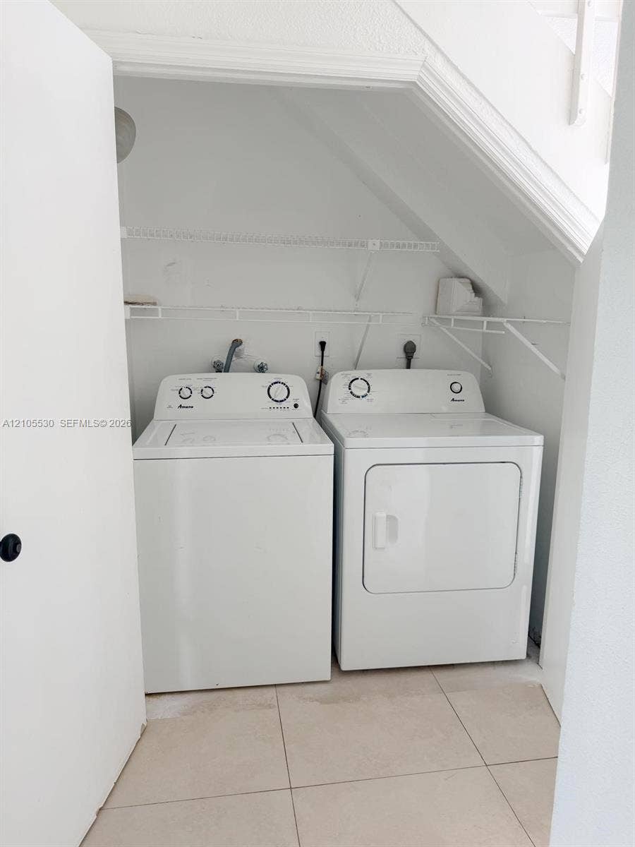 Laundry area featuring a washer and dryer, tile flooring, and integrated shelving