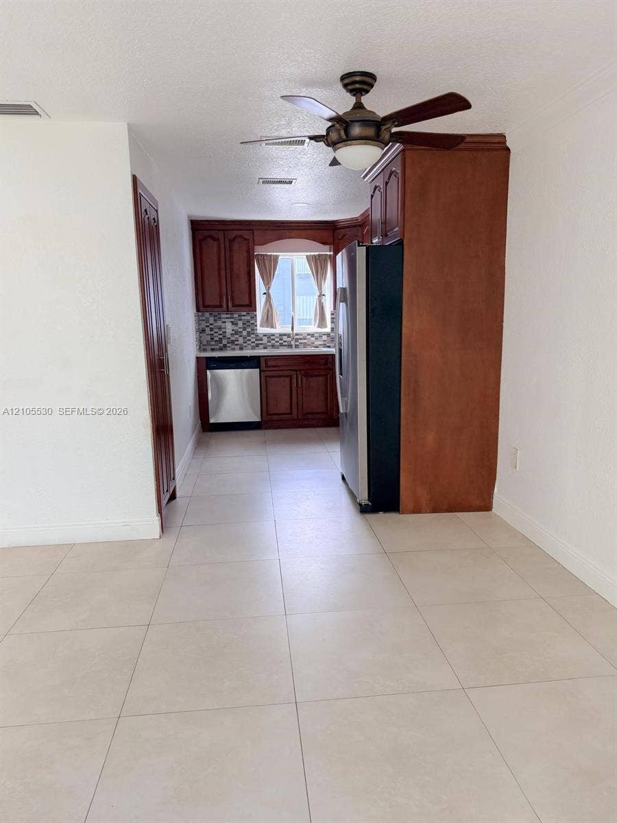 Kitchen area with wood-finish cabinetry, stainless steel appliances, and a mosaic tile backsplash