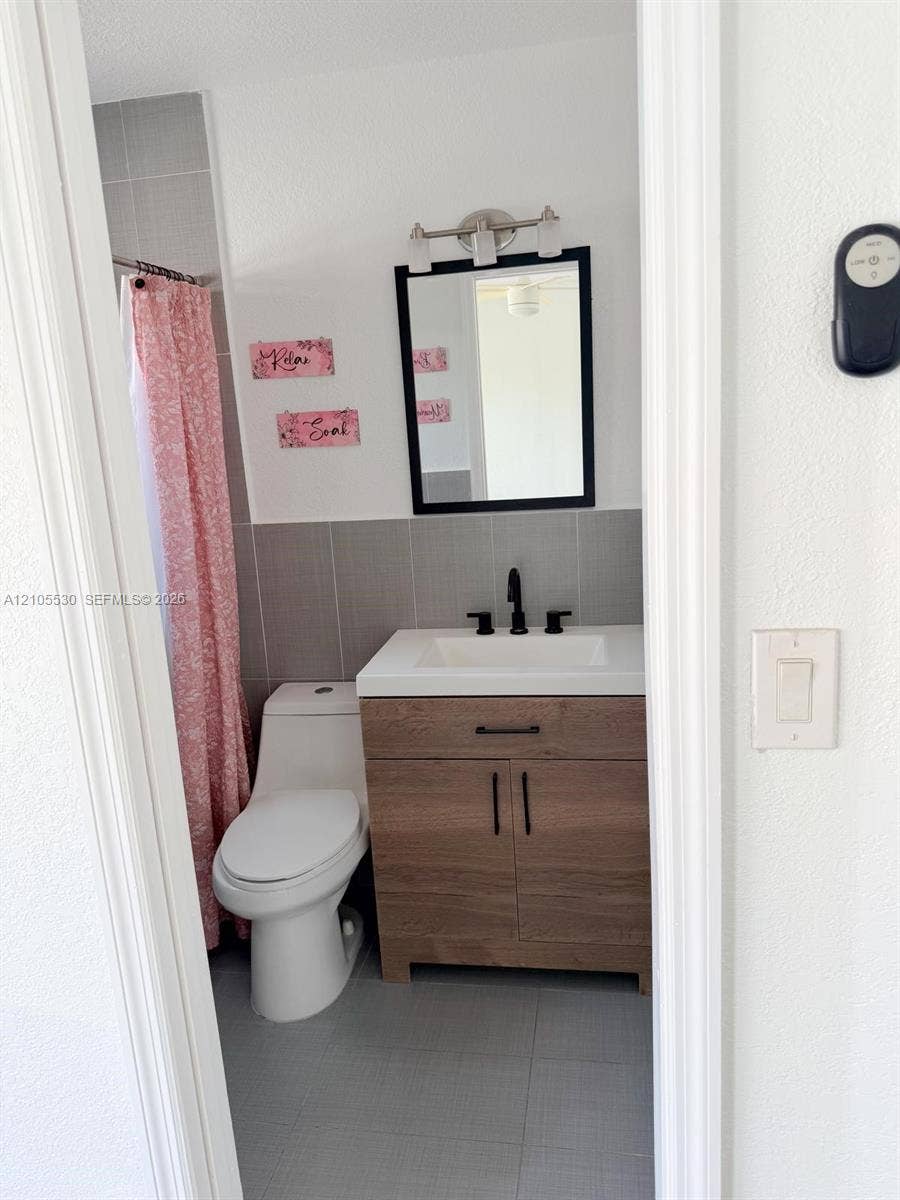 Vanity with wood-finish cabinetry, white countertop, and black fixtures