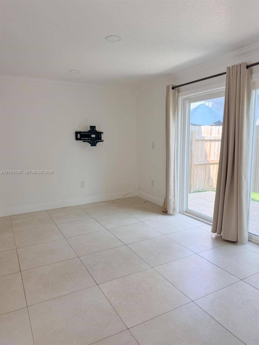 Recessed lighting, light-toned tile flooring, and sliding glass doors to exterior