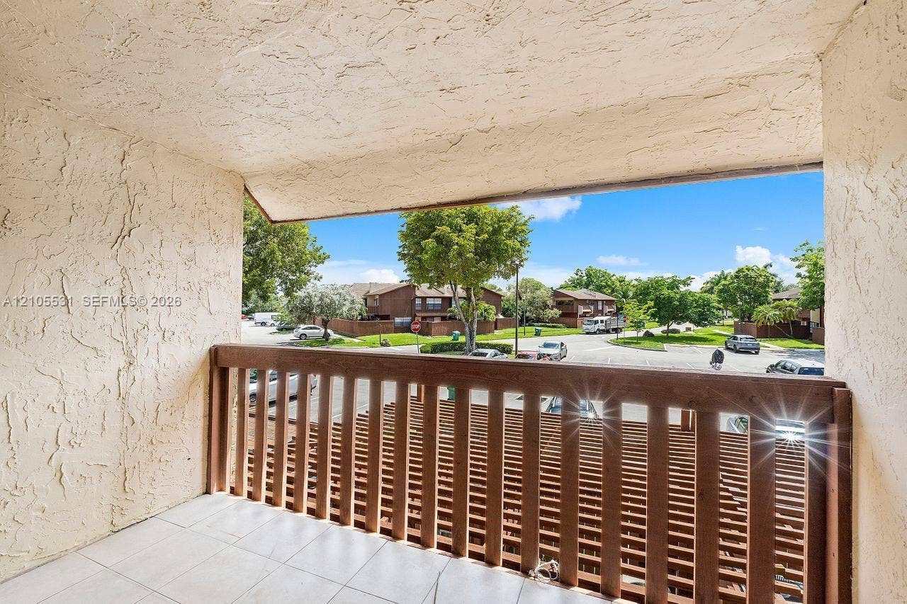 Balcony featuring a wood-finish railing, textured wall finish, and tiled flooring