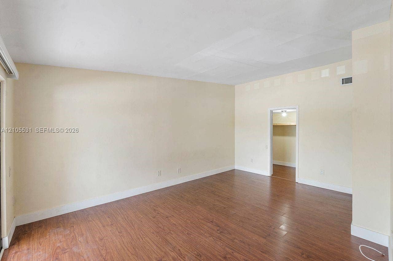 Spacious room featuring wood-finish flooring, light-toned walls, and white trim