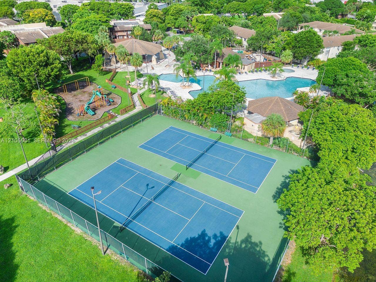 Dual tennis courts, playground area, and a large swimming pool