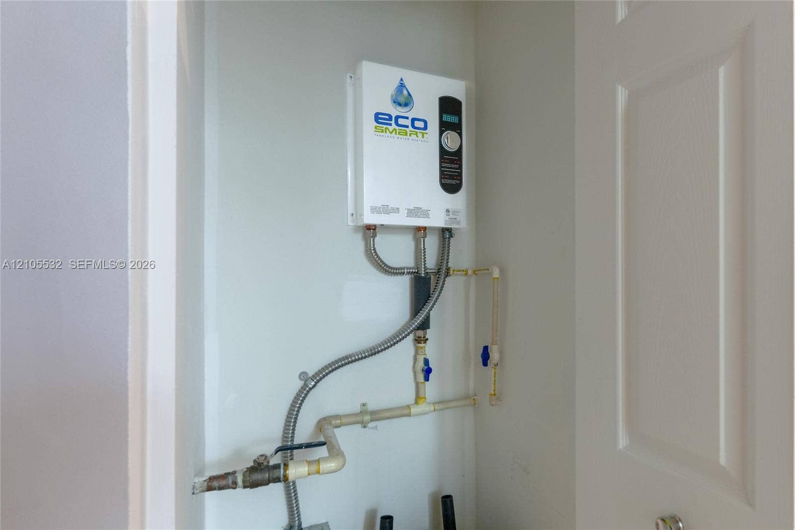 Tankless electric water heating system featuring a digital temperature control interface and integrated plumbing connections