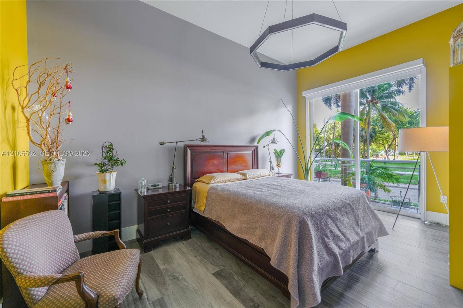 Wood-finish flooring, high ceilings, large sliding glass door with balcony access, and a geometric pendant light fixture