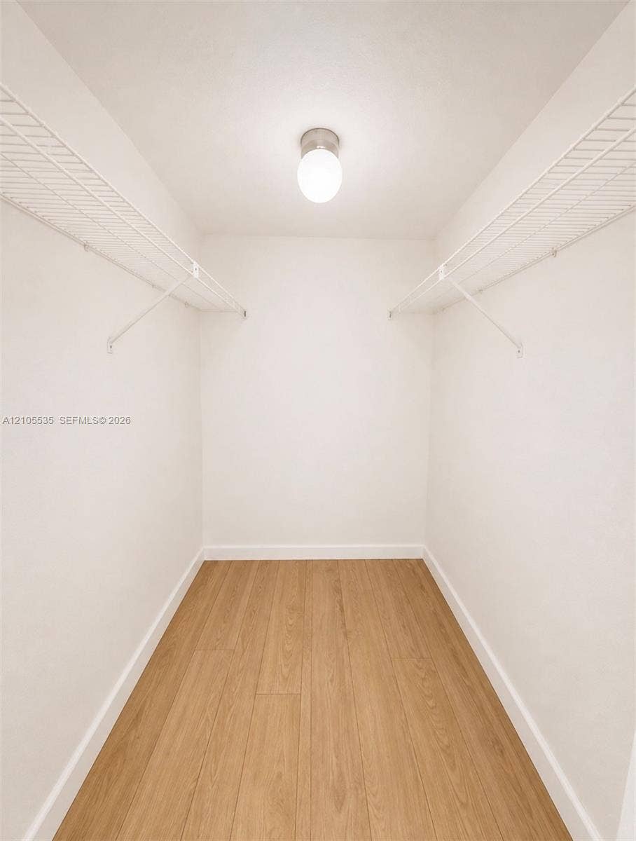 Recessed ceiling light, white walls, wood-finish flooring, and wire shelving