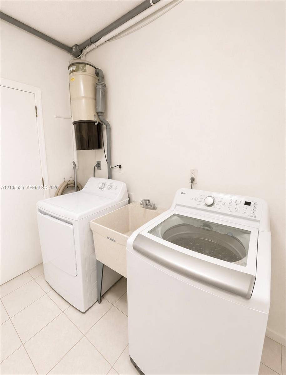 Dedicated laundry area featuring a utility sink, a top-load washing machine, a front-load dryer, and tile flooring