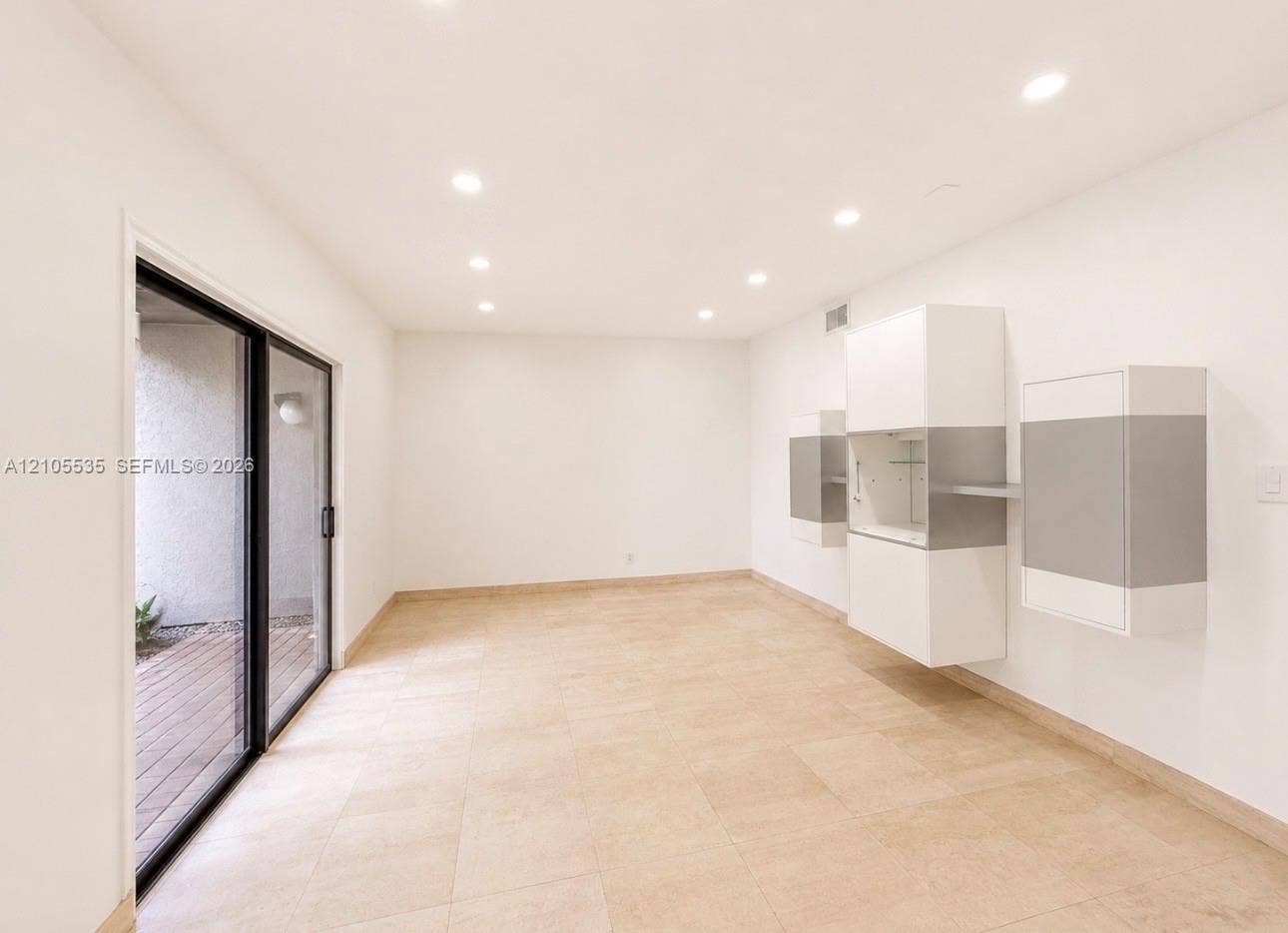 Recessed ceiling lighting, sliding glass door, light-toned floor tile, and built-in wall cabinetry