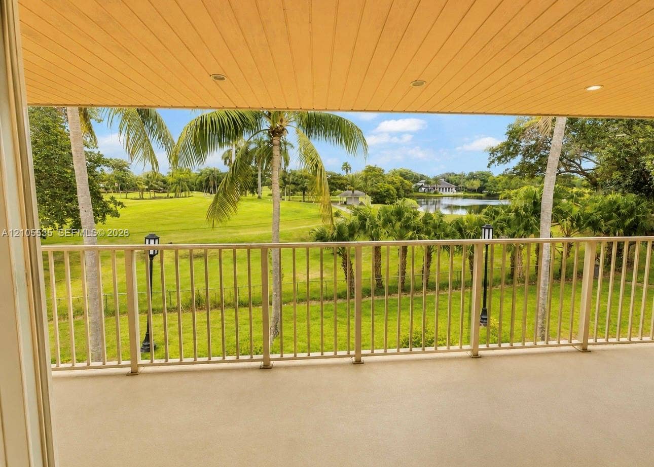 Covered balcony with recessed lighting, metal railing, and a scenic golf course and pond backdrop