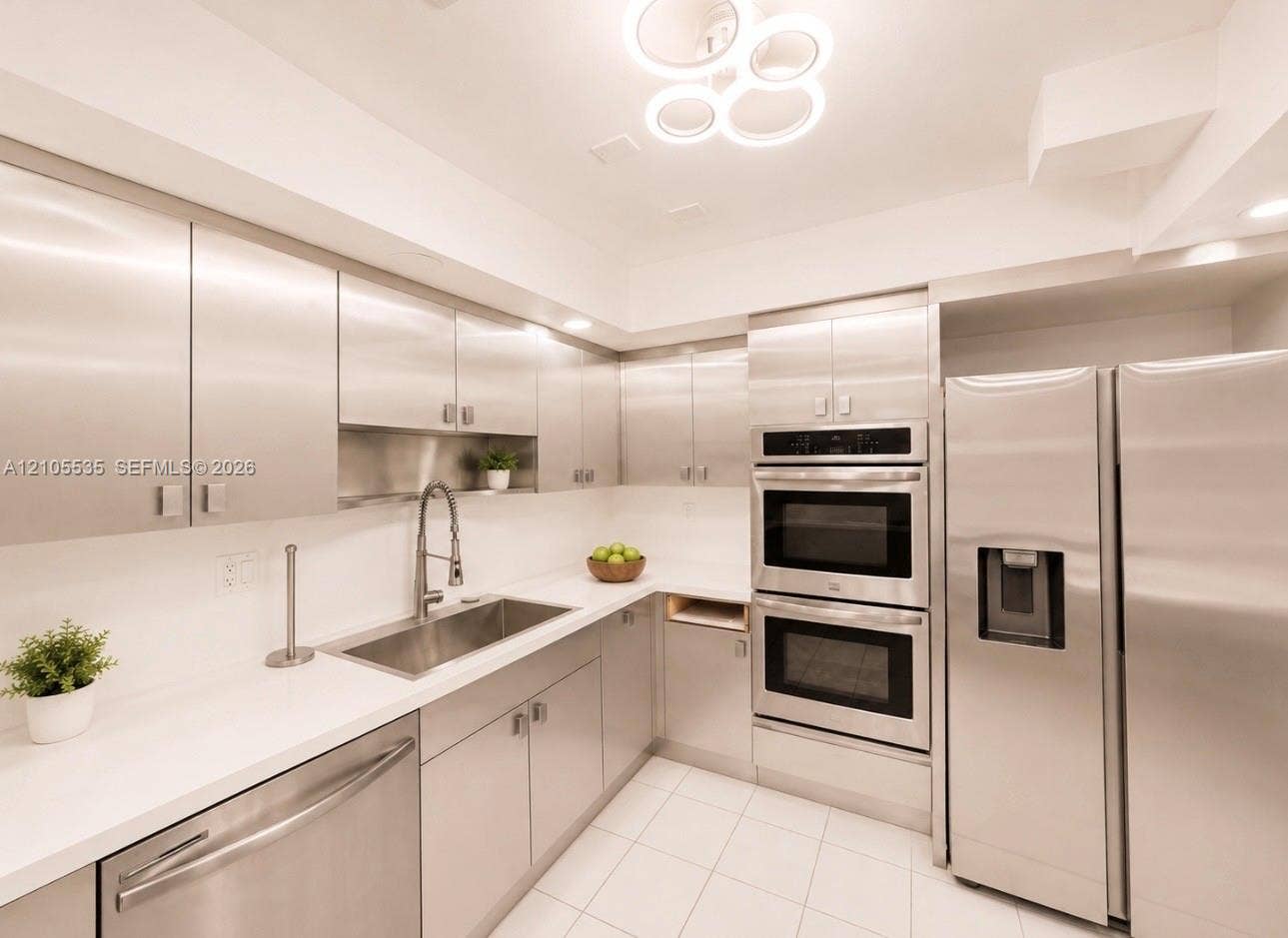Stainless steel appliances, white tile flooring, white countertops, built-in double ovens, and a contemporary ceiling fixture