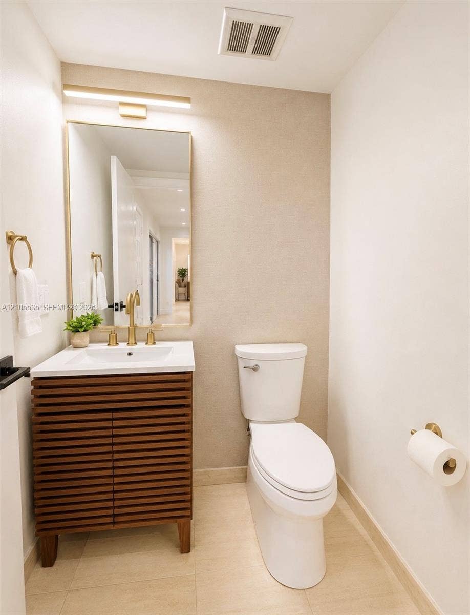 Modern vanity with slatted wood-finish cabinetry, white integrated sink, and brass-finish fixtures