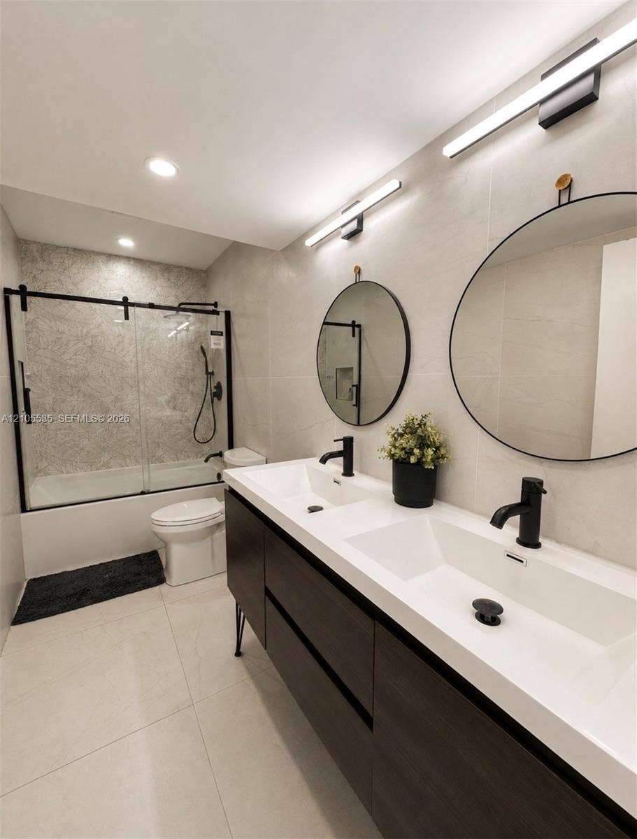 Dual vanity with integrated sinks, dark wood-finish cabinetry, and matte black fixtures