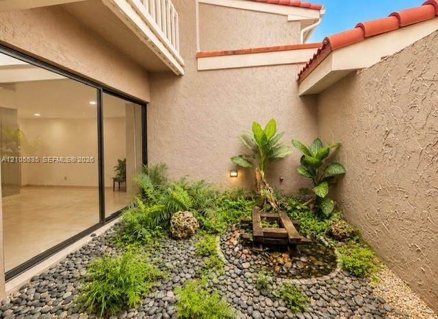 Private courtyard garden featuring a water element, varied lush plantings, and black river stones