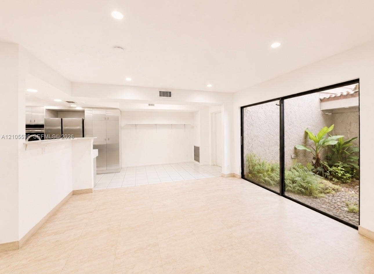 Recessed lighting, tile flooring, full-height glass panels, and an enclosed courtyard with established plantings