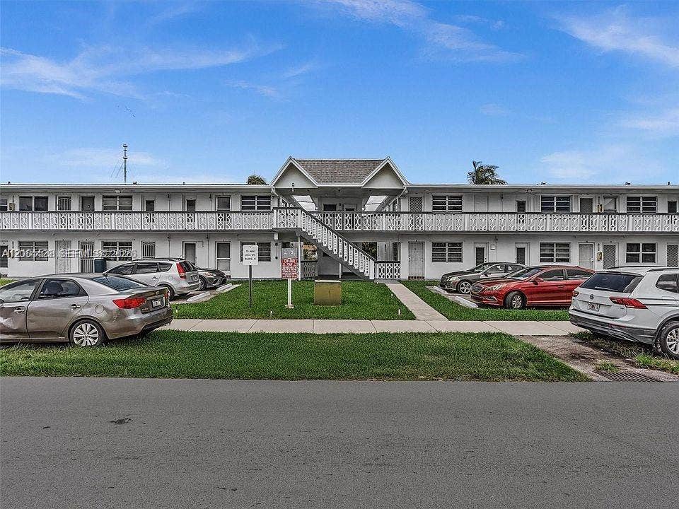Two-story building with white exterior finish, featuring multiple entry doors and ground-level windows