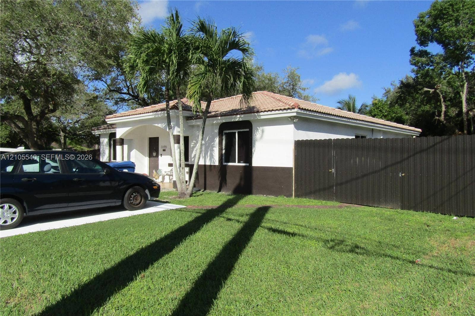 21935 SW 102nd Avenue, Cutler Bay, FL 33190 Manicured front lawn with mature trees, a paved driveway, and a privacy fence