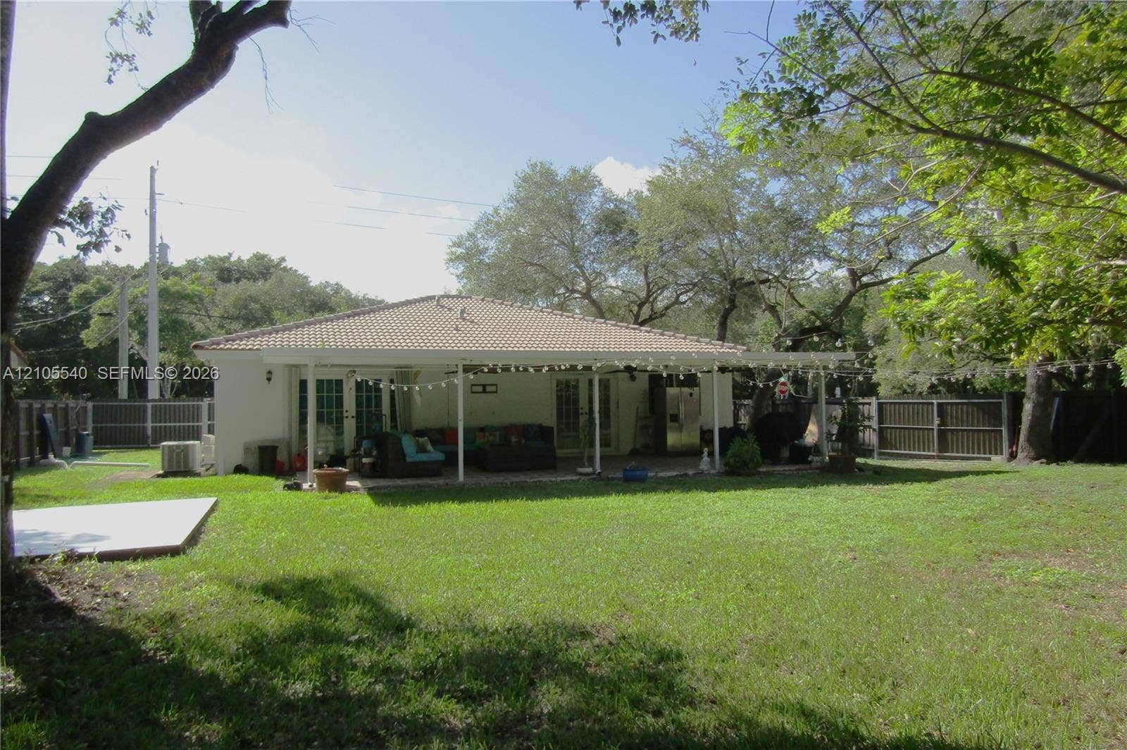 21935 SW 102nd Avenue, Cutler Bay, FL 33190 Expansive grass lawn with mature trees, a tile roof, and a covered back patio with support columns
