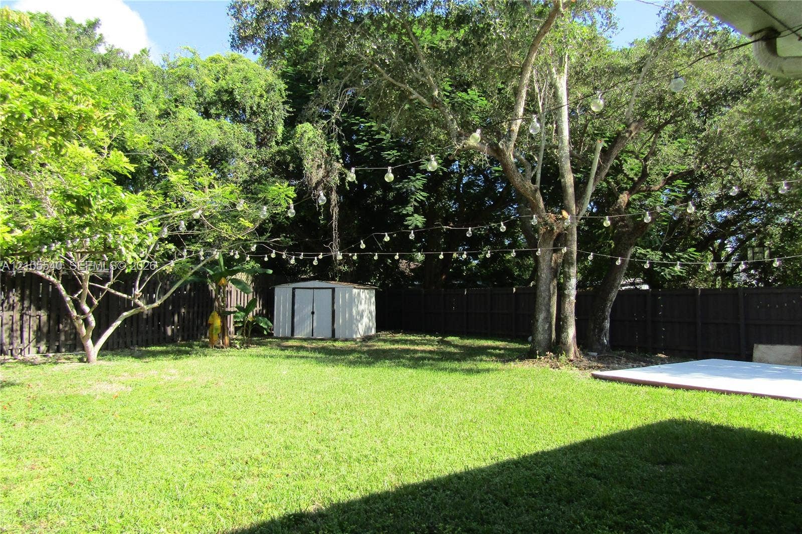 21935 SW 102nd Avenue, Cutler Bay, FL 33190 Expansive backyard featuring a lush lawn, mature trees, a privacy fence, and a storage shed