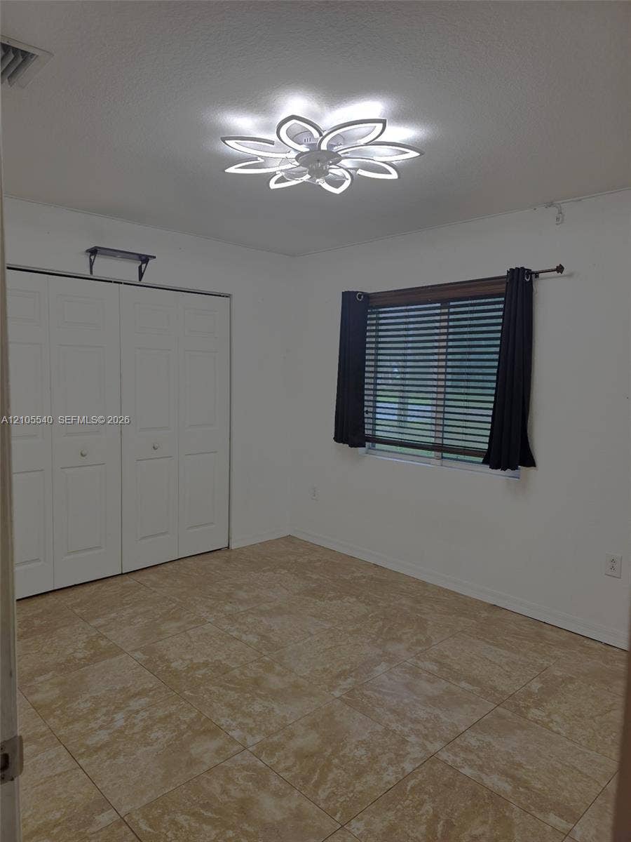 21935 SW 102nd Avenue, Cutler Bay, FL 33190 Neutral-toned tile flooring, contemporary ceiling light fixture, white bi-fold closet doors, and a window with blinds