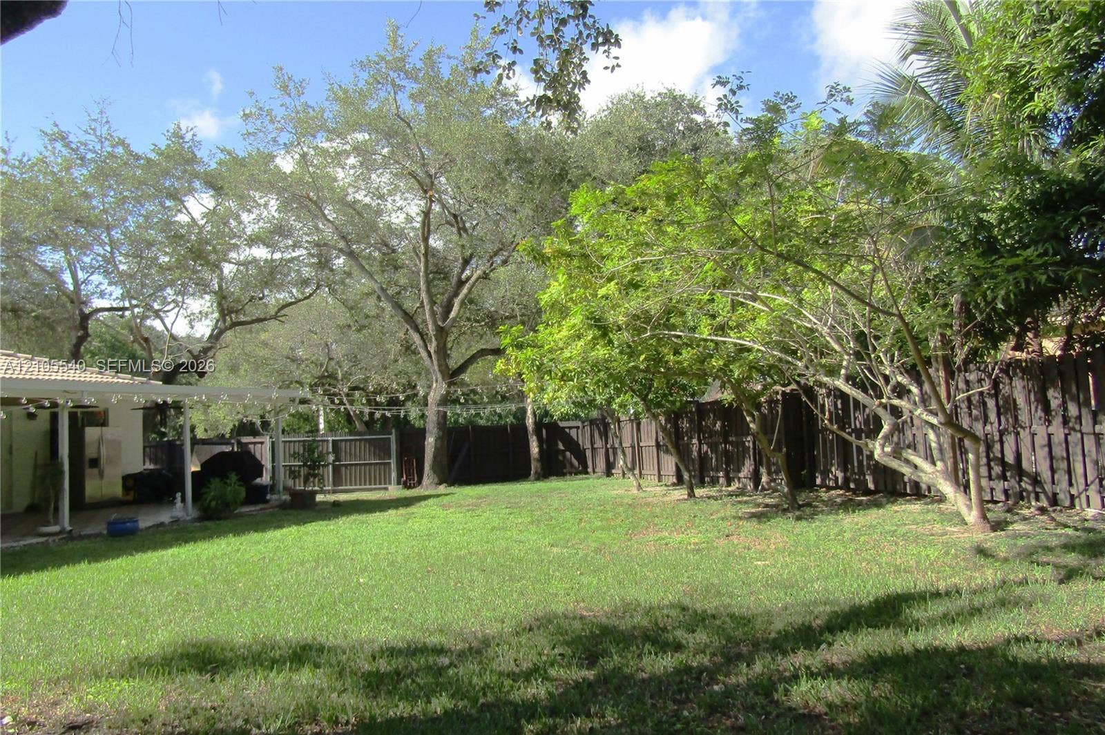 21935 SW 102nd Avenue, Cutler Bay, FL 33190 Spacious backyard featuring a manicured lawn, established trees, and a privacy fence