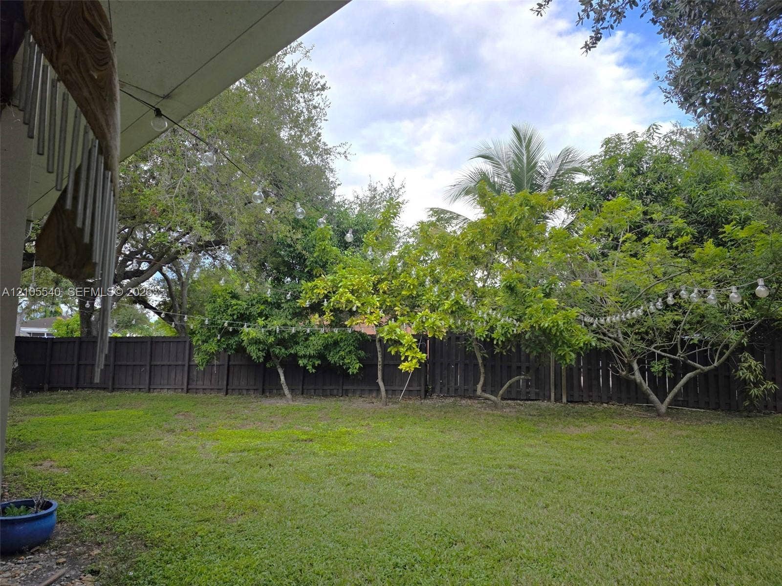 21935 SW 102nd Avenue, Cutler Bay, FL 33190 Expansive backyard featuring a lush lawn, mature trees, and a wooden privacy fence