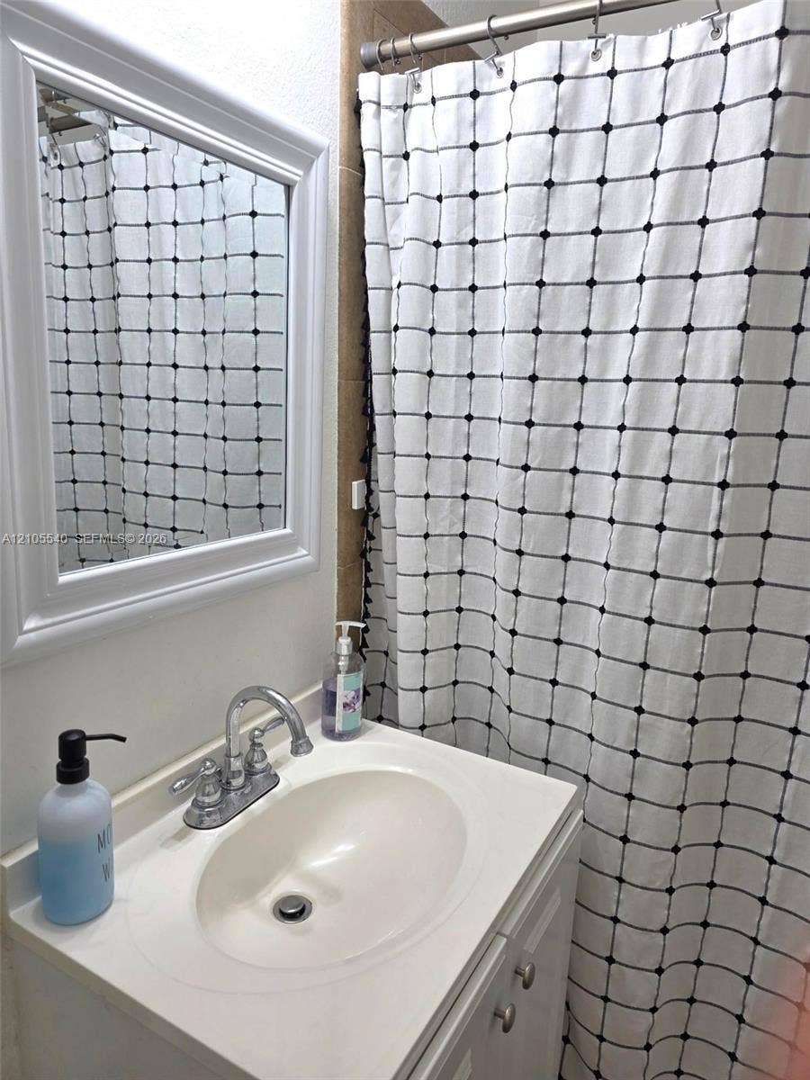 21935 SW 102nd Avenue, Cutler Bay, FL 33190 Vanity with integrated sink and chrome faucet, framed mirror, and tiled shower surround