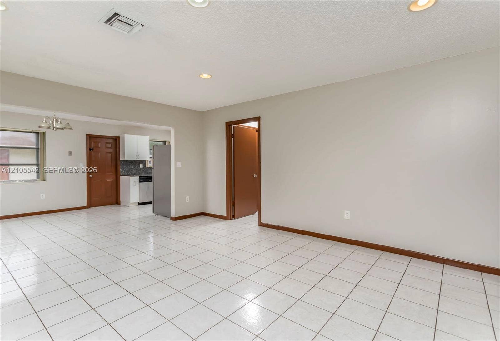 White tile flooring throughout, recessed lighting, and a kitchen with stainless steel appliances