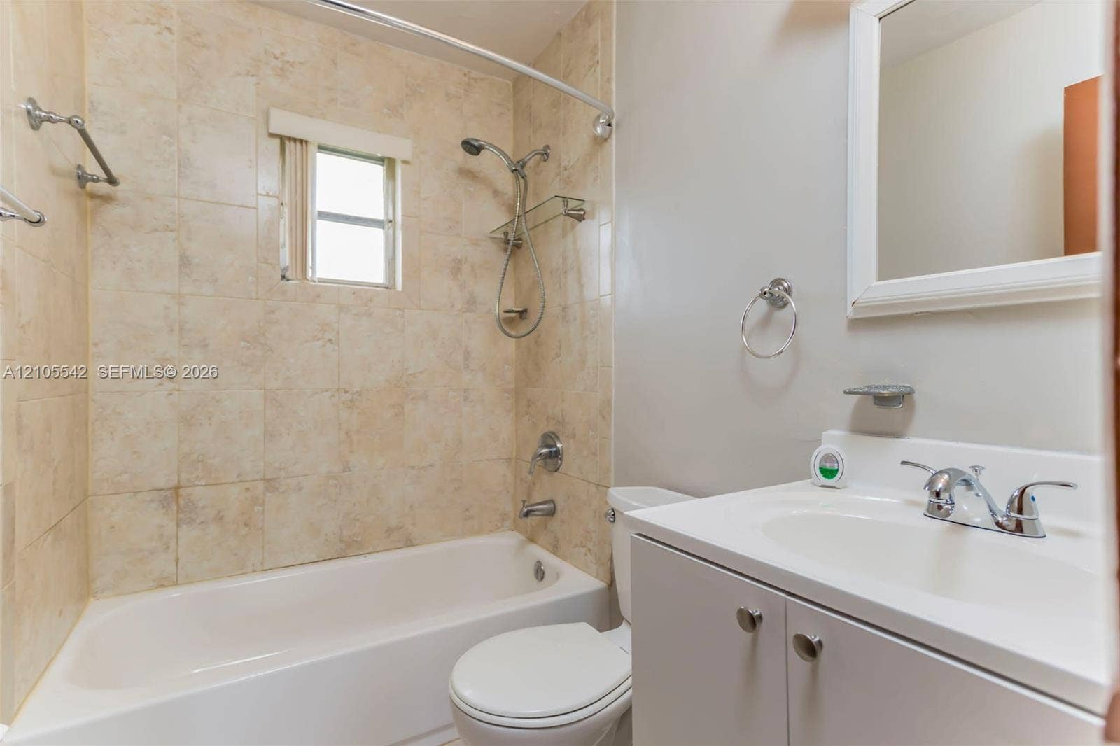 Full bathroom featuring a white vanity with integrated sink, chrome faucet, tiled shower surround, and a fixed window