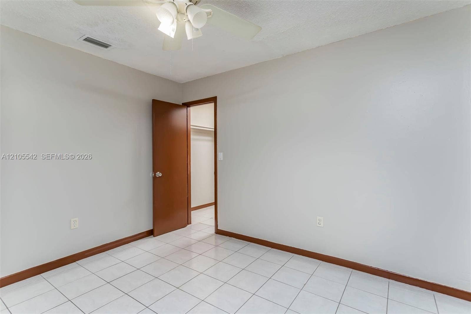 White square tile flooring, neutral wall tones, wood-finish baseboards, and a ceiling fan with integrated lighting