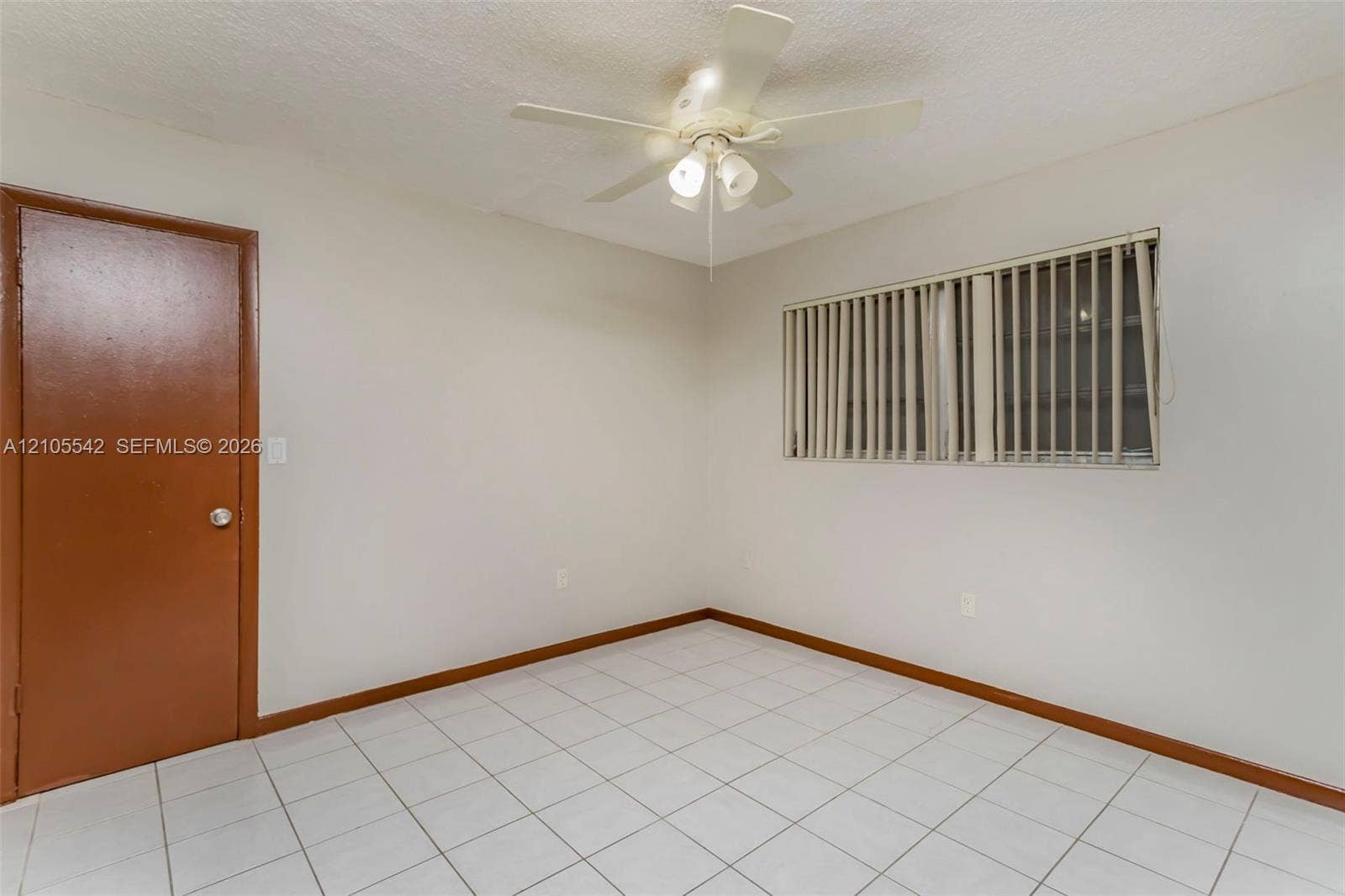 White tile flooring, ceiling fan with integrated lighting, window with blinds, and a solid door