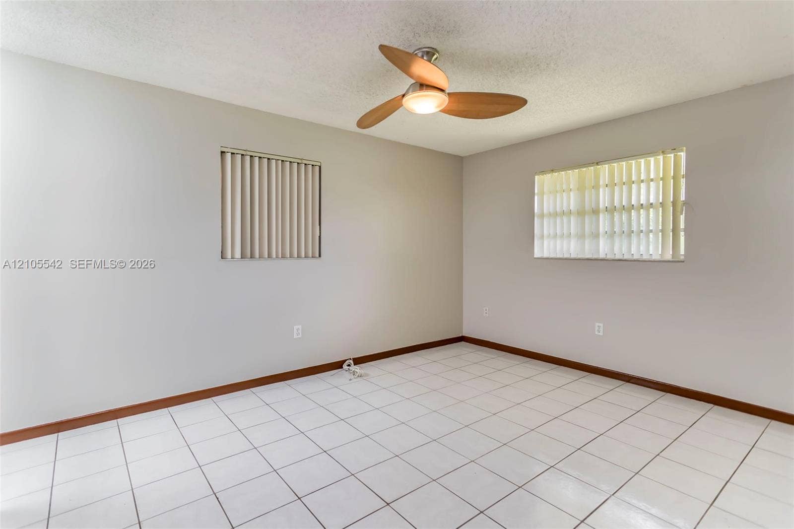 White square tile flooring, light gray wall paint, and two windows with vertical blinds
