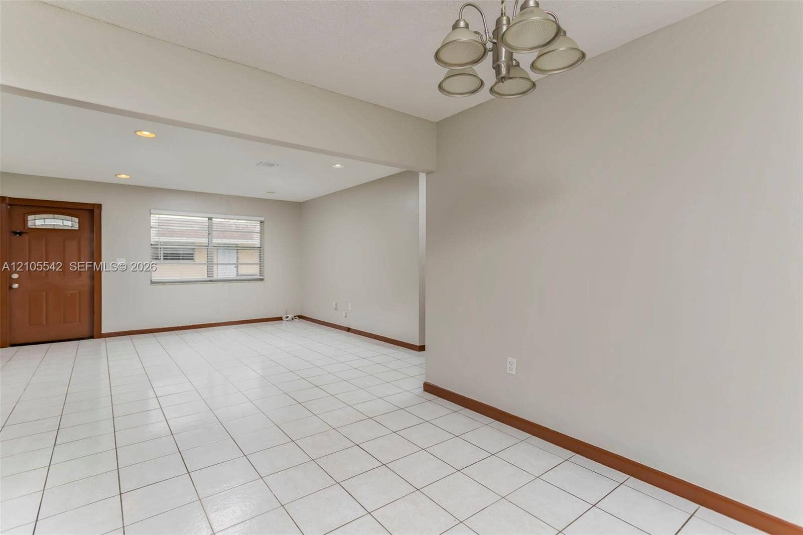 White tile flooring, wood-finish entry door with glass inserts, recessed lighting, and a multi-light ceiling fixture