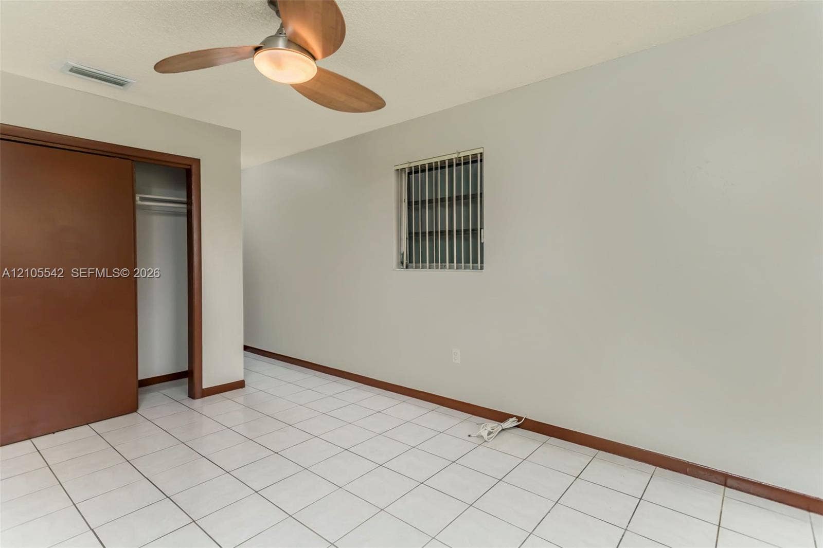 White square tile flooring, wood-finish ceiling fan with integrated lighting, sliding closet door, and window with horizontal blinds