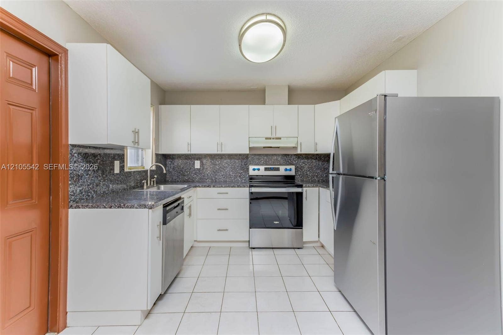 U-shaped kitchen with white cabinetry and dark stone countertops