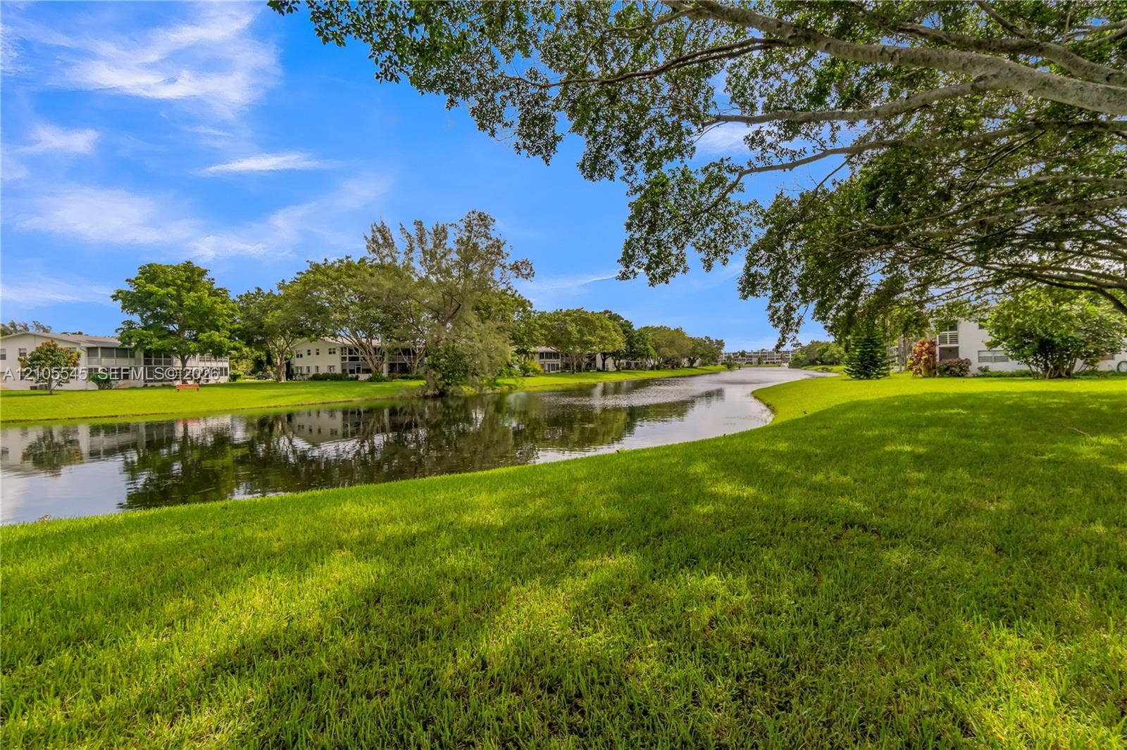 222 Tilford A, #222, Deerfield Beach, FL 33442 Expansive green space with manicured lawn, mature trees, and a tranquil water feature
